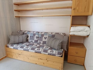 A wooden sofa with patterned cushions in a room with a tiled floor and a wooden cabinet. - Paradiski closed to the slopes and shop vallandry (LANDRY)