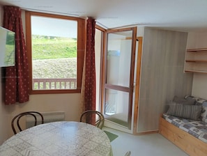A room with a dining table, chairs, a sofa, a sliding glass door to a balcony, and a TV on the wall. - Paradiski closed to the slopes and shop vallandry (LANDRY)