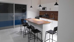 Una cocina moderna con una isla central, taburetes de bar e iluminación colgante.
