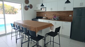 Una cocina moderna con comedor, armarios blancos, refrigerador negro y ventilador de techo.