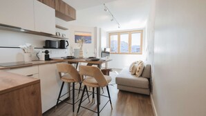 A modern kitchen with a dining area, wooden cabinets, and a view of the outdoors. - Magnificent 3-room apartment 31m², south-east facing, mountain/resort view (VAL THORENS)