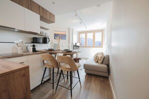 A modern kitchen with a dining area, wooden cabinets, and a view of the outdoors. - Magnificent 3-room apartment 31m², south-east facing, mountain/resort view (VAL THORENS)