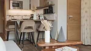 A modern kitchen with a built-in microwave, a coffee machine, and a dining area with a wooden table and chairs. - Magnificent 3-room apartment 31m², south-east facing, mountain/resort view (VAL THORENS)