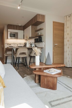 A modern kitchen with a built-in microwave, a coffee machine, and a dining area with a wooden table and chairs. - Magnificent 3-room apartment 31m², south-east facing, mountain/resort view (VAL THORENS)