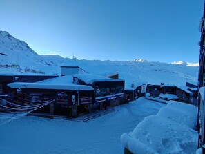 A snow-covered building with signage for a supermarket and ski rental services. - Magnificent 3-room apartment 31m², south-east facing, mountain/resort view (VAL THORENS)