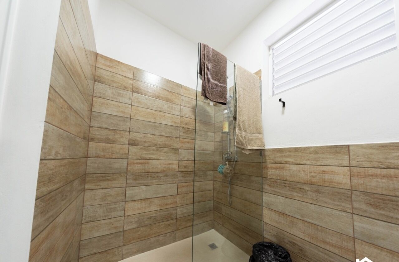 A shower with wooden tiles, a glass door, and a towel hanging on the wall.