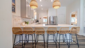 A modern kitchen with a large island, bar stools, pendant lights, and stainless steel appliances. - Walk2Beach•Free Golf Cart•YOLO Bikes (Santa Rosa Beach)