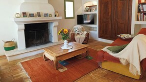 A cozy living room with a fireplace, a television, a wooden coffee table, and a comfortable sofa. - Au coeur des ocres - Charming vacation home (Roussillon)