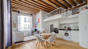 A modern apartment with a dining area, kitchen, and a balcony.