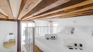 A modern bedroom with a large bed, white bedding, and a wooden ceiling.