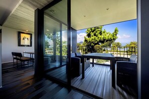 A modern room with a glass wall, a wooden deck, and outdoor furniture.