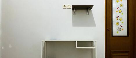 A room with two beds, a desk, an air conditioner, a trash bin, and a door with a decorative sticker.