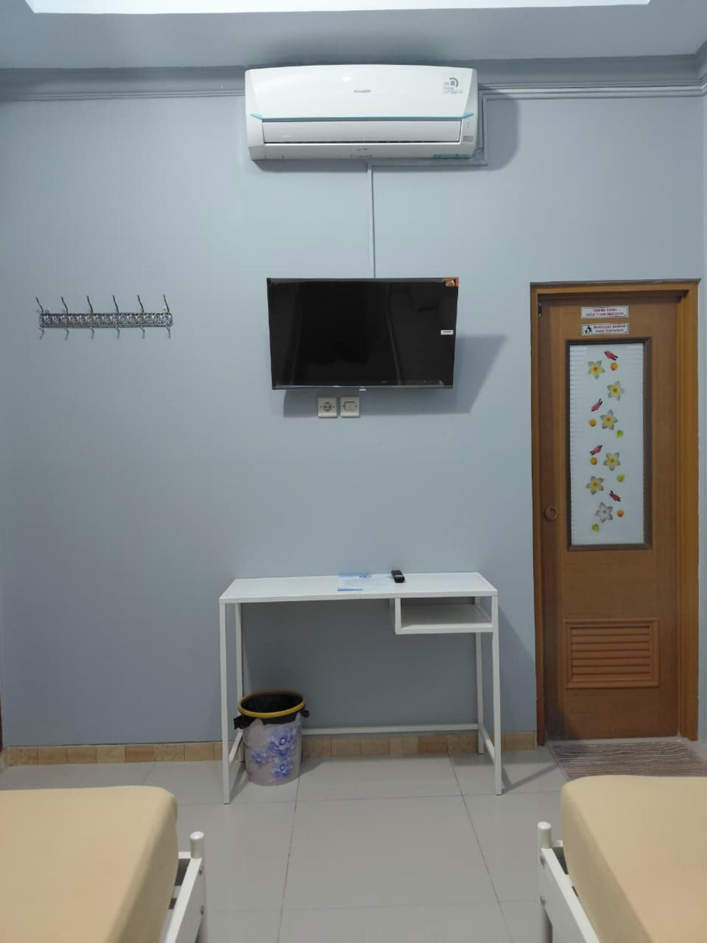 A room with a bed, a desk, a television, and an air conditioner.