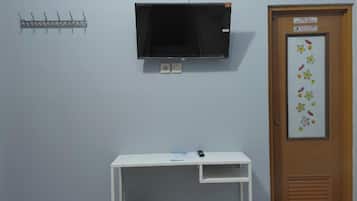 A room with a bed, a desk, a television, and an air conditioner.