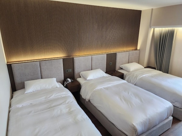 Kamar Triple Deluks | Seprai premium, selimut bulu angsa, busa memori, dan meja kerja