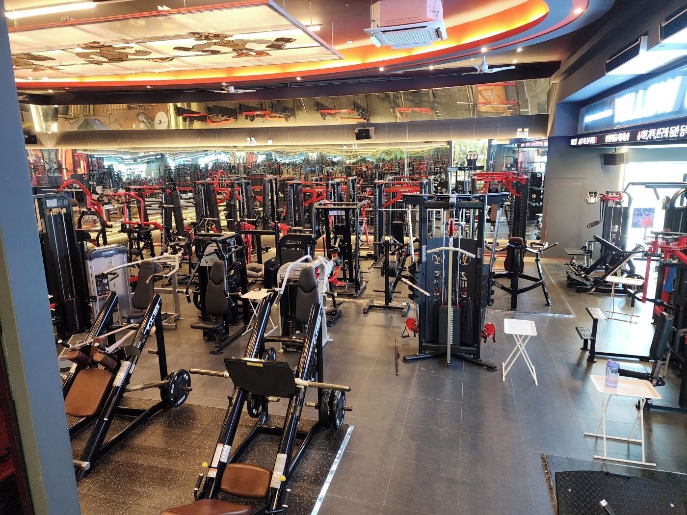A gym with various exercise machines, a mirrored wall, and a ceiling with a unique design.