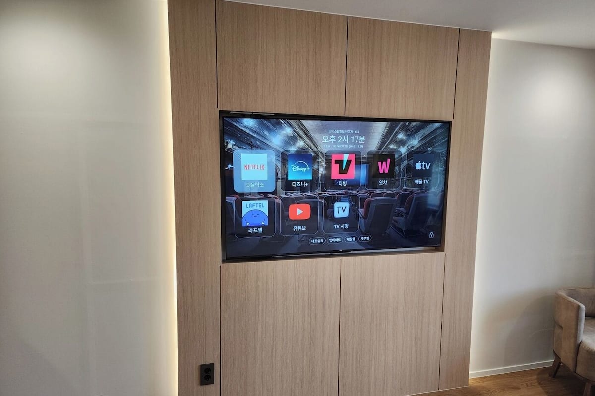 A flat-screen TV mounted on a wooden wall with a modern design.