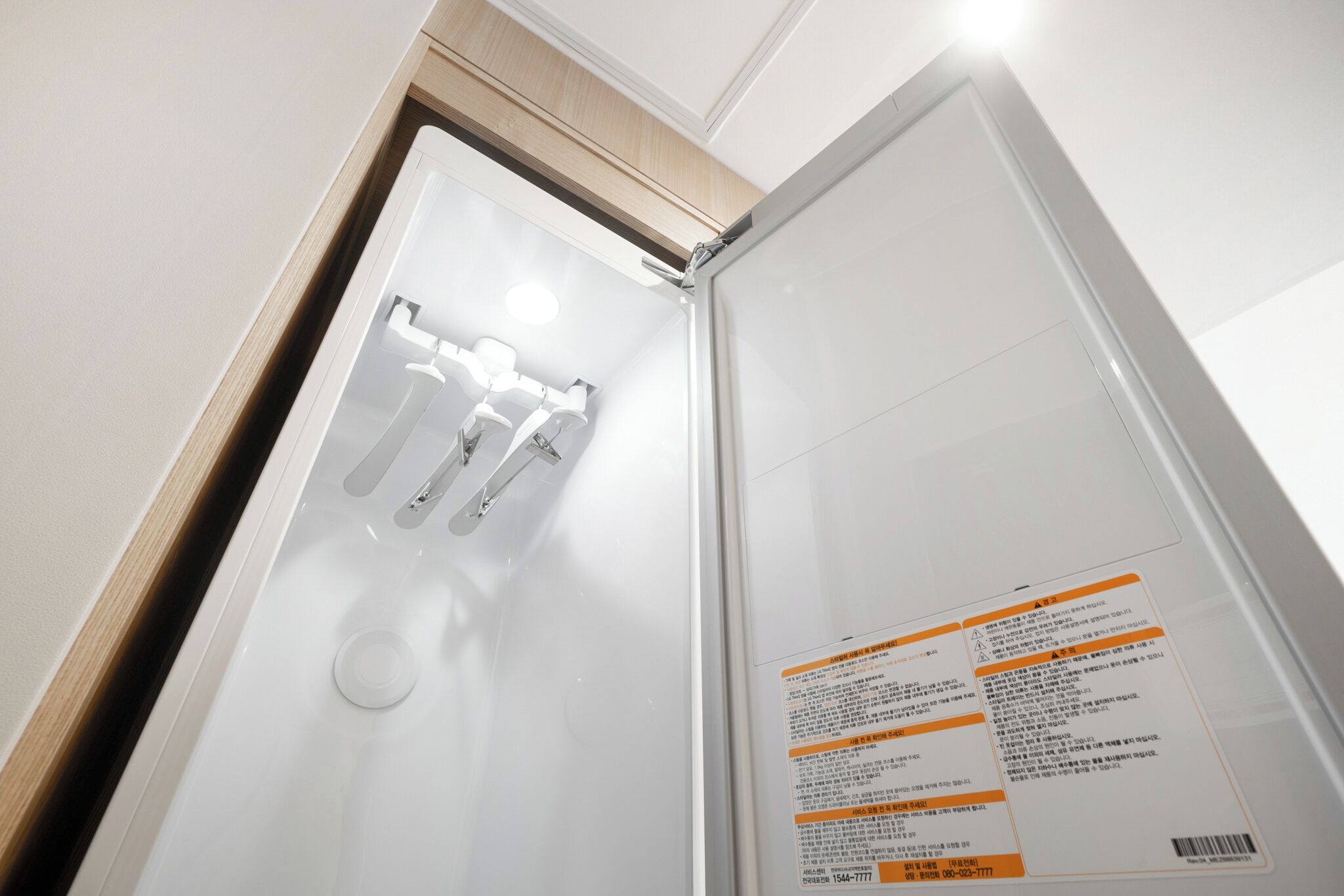 Habitació d'hotel amb una porta blanca, un mirall i un quadre de control fixat a la paret amb instruccions.