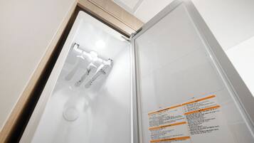 Habitació d'hotel amb una porta blanca, un mirall i un quadre de control fixat a la paret amb instruccions.