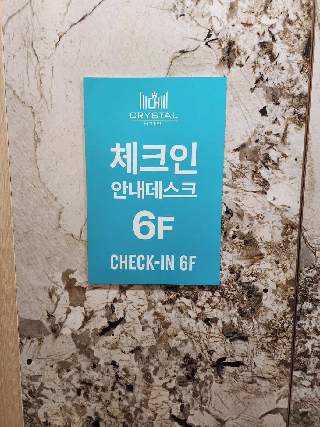 Indicador de l'àrea de recepció de l'Hotel Crystal, amb text en coreà i fons de paret de marbre.