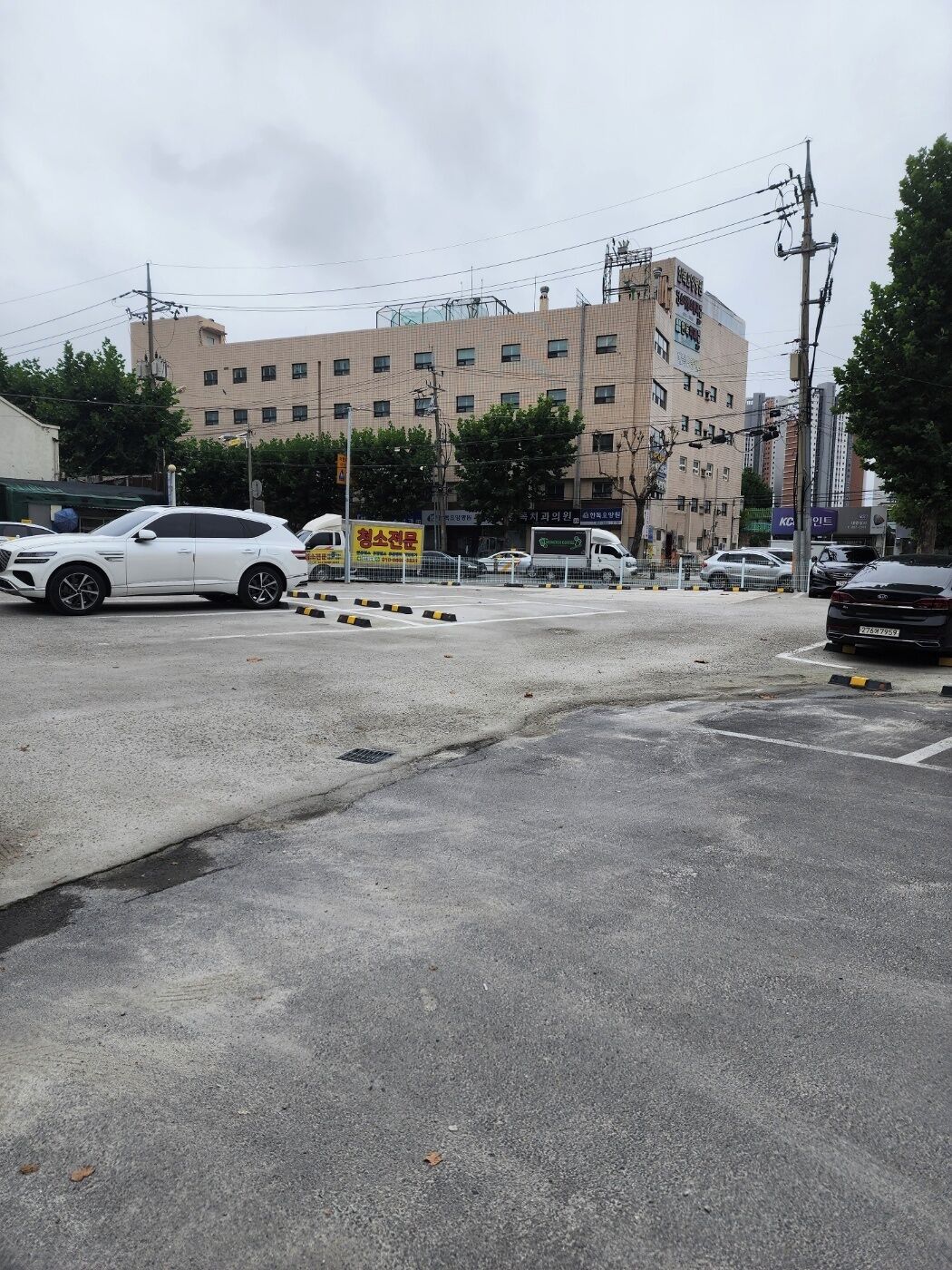 Un estacionamiento con varios coches, un edificio de varios pisos y diferentes letreros.
