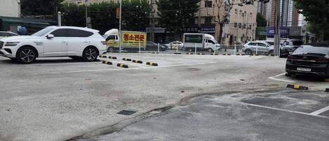 Un estacionamiento con varios coches, un edificio de varios pisos y diferentes letreros.