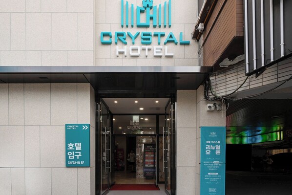 The exterior of the Crystal Hotel with a check-in sign and directional arrows.