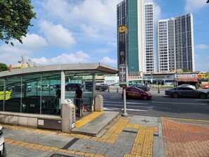 A bus stop with a shelter, a tall building in the background, and a street with cars.