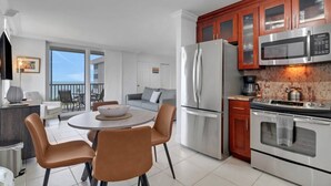 Una cocina moderna con electrodomésticos de acero inoxidable, un comedor con una mesa redonda y sillas, y un balcón con vistas.