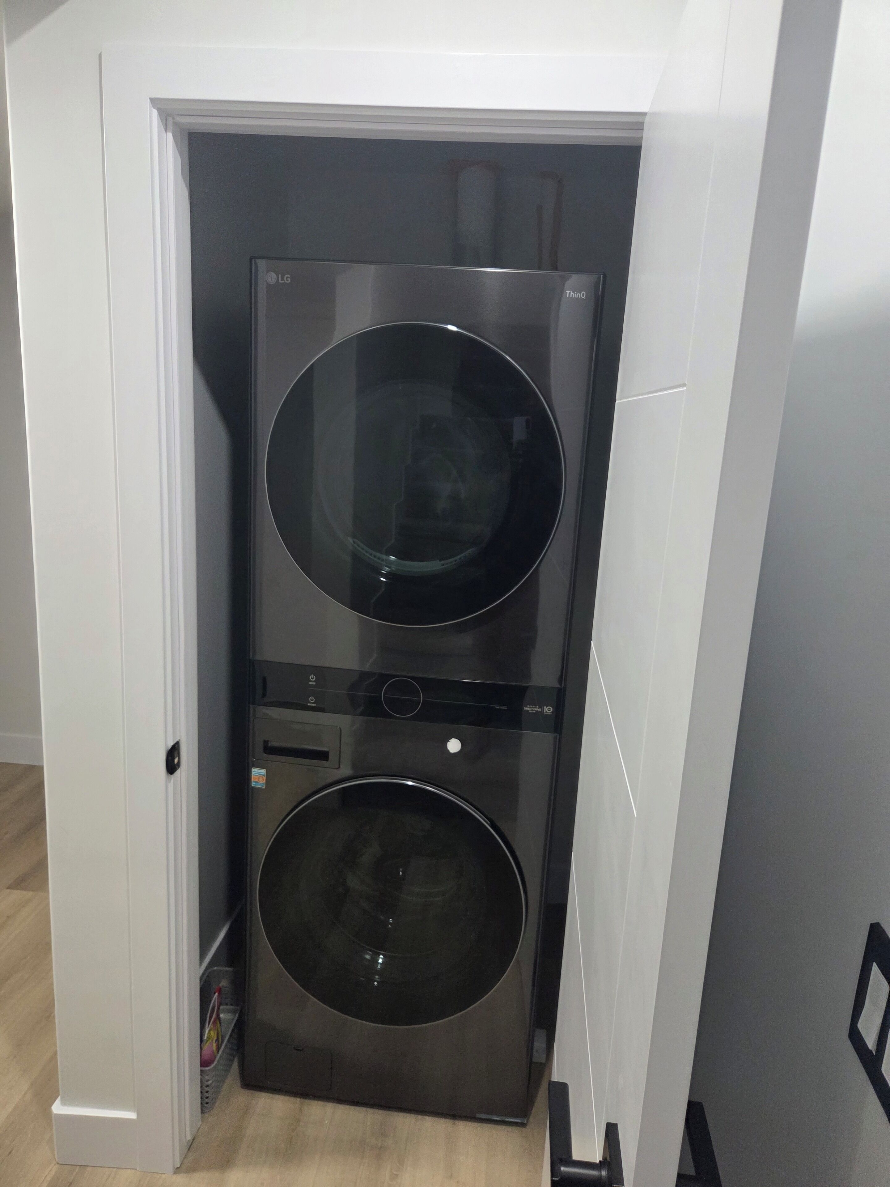 Een kleine, moderne wasruimte met een ingebouwde wasmachine en droger, gelegen in een smalle gang.