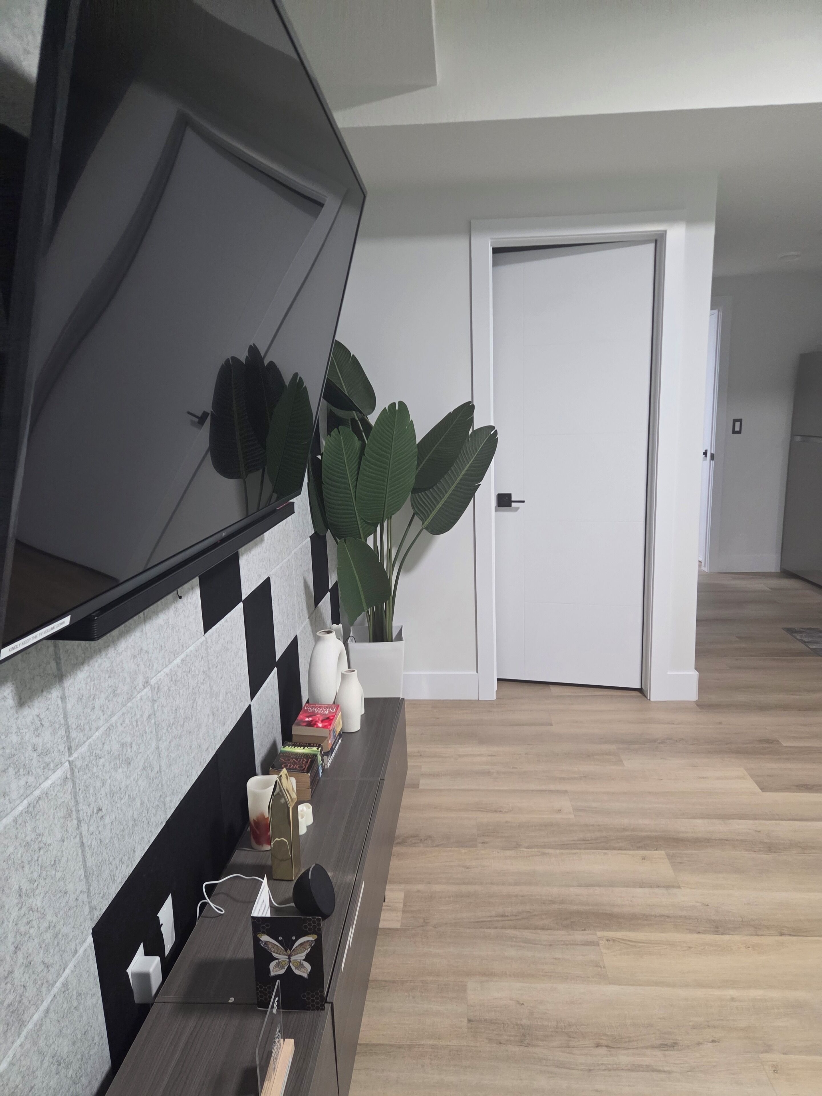 Una cocina moderna con un salpicadero blanco y negro, encimera de madera y una planta en maceta.