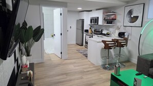 A modern kitchen with white cabinets, a built-in oven, and a microwave. There is a dining area with a green table and two wooden chairs. A large potted plant is visible in the corner. - Tranquil Getaway.

Home located near golf course.Enjoy this calm & stylish suite (Edmonton)