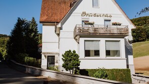 A white building with a red-tiled roof, a balcony with wooden railings, and a sign that reads "Hofhaus".
