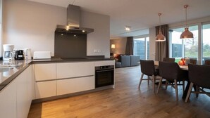 Una cucina moderna con forno integrato, macchina del caffè e tostapane. C'è un'area pranzo con tavolo e sedie.