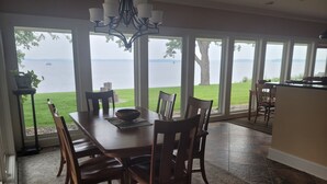 A dining area with a view of the sea, a chandelier, and a large window.