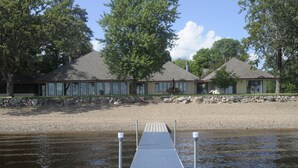 A dock leading to a row of cabins with large windows, a stone wall, and a clear sky.