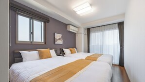 A hotel room with two beds, a large window with blinds, an air conditioning unit, and a curtain on the window. - HOTEL KOMACHI Higashi Nippori (Tokyo)