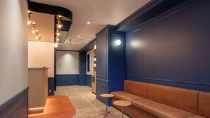 A hallway with a blue wall, a brown bench, and a small round table. - HOTEL KOMACHI Higashi Nippori (Tokyo)