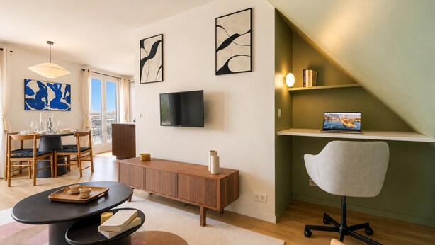 A modern living room with a dining area, a flat-screen TV, and artwork on the walls.