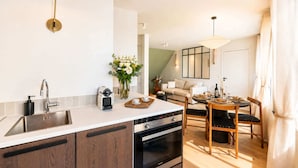 A modern kitchen with a built-in oven, a coffee machine, and a dining area with a table set for two.