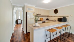 Una cocina moderna con una isla central, taburetes de madera y un reloj en la pared.
