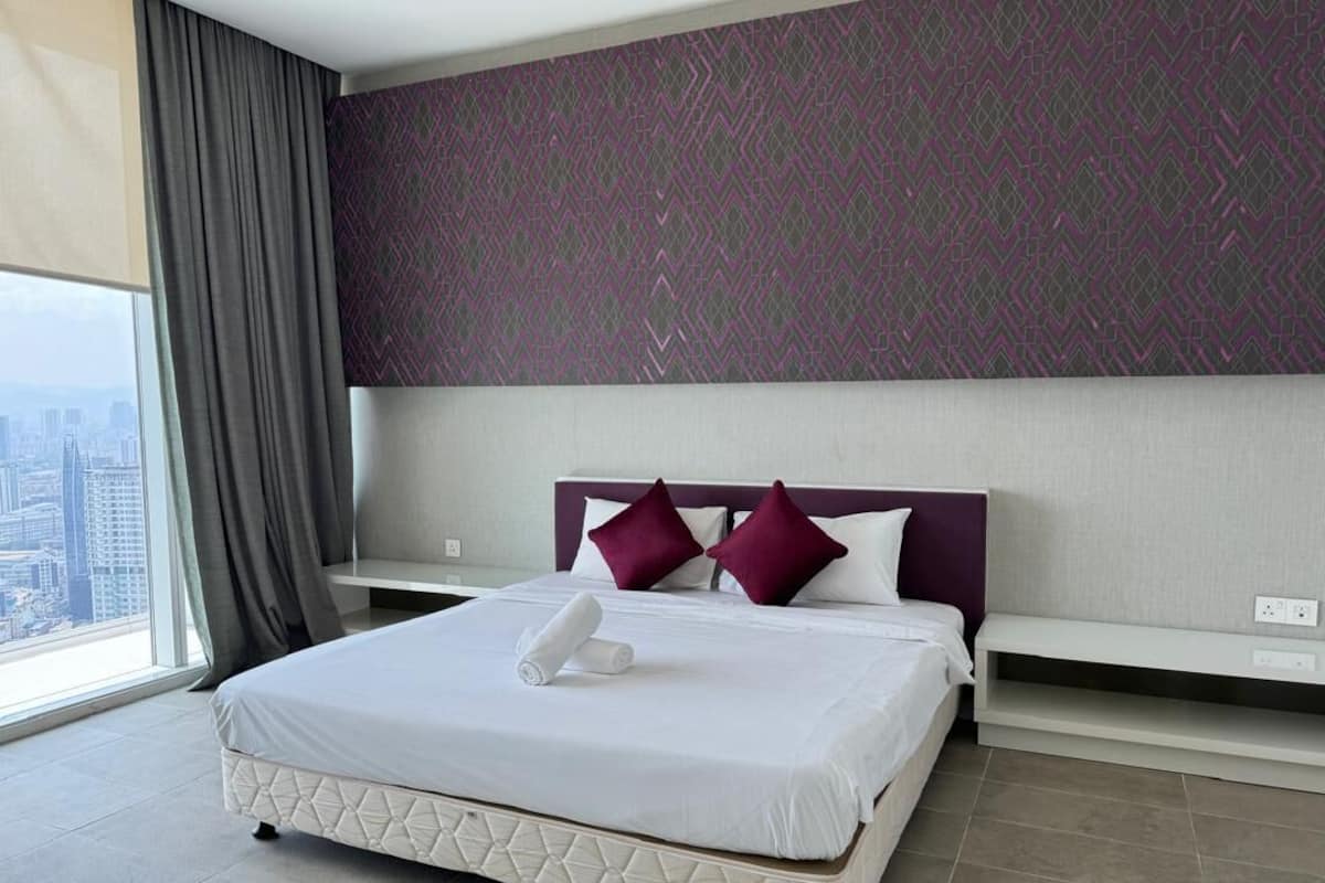 A hotel room with a large bed, a city view, a patterned wall, and a modern design.