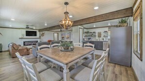 Un salon spacieux avec une table à manger en bois entourée de chaises, une cheminée et un téléviseur.
