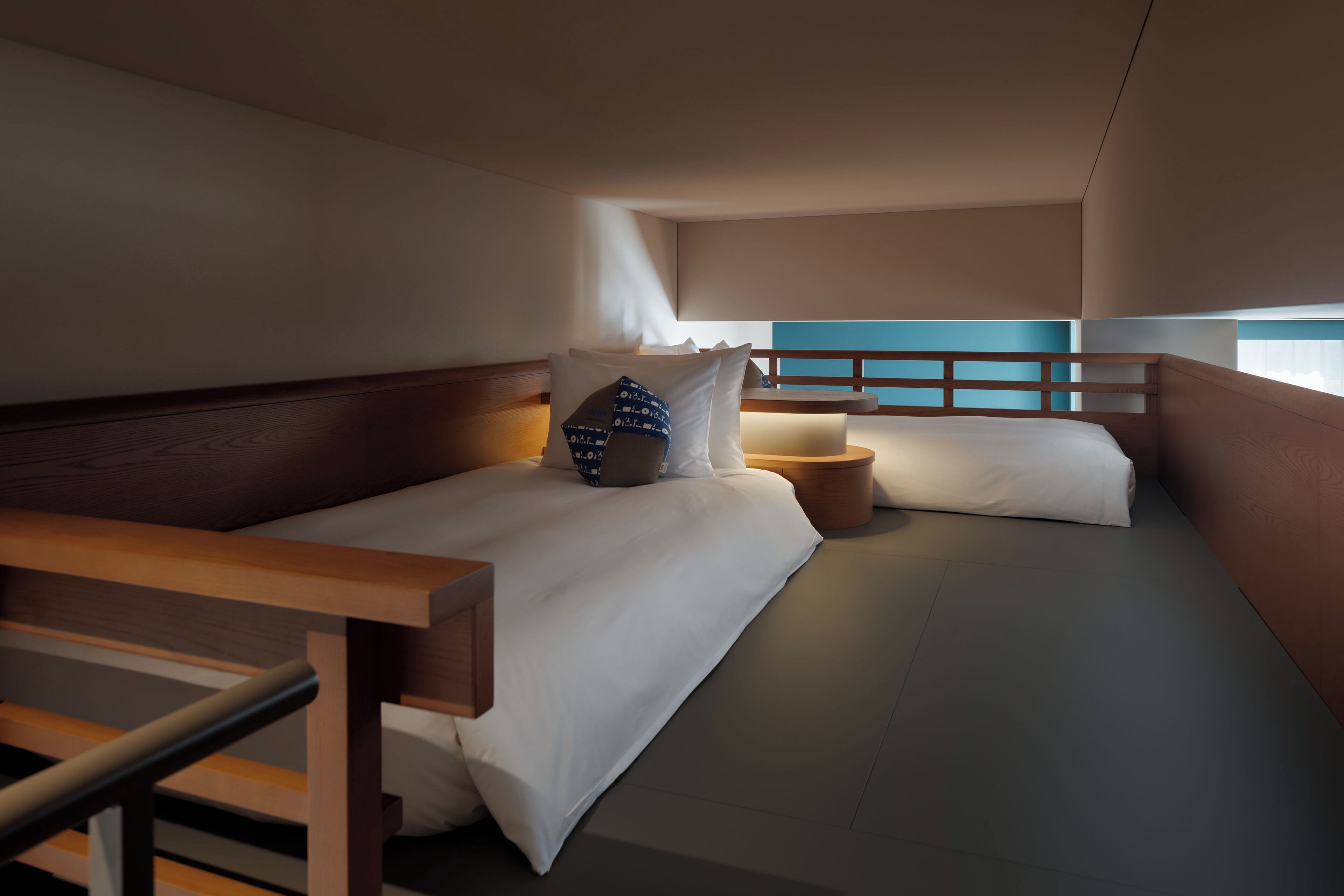 Quarto de hotel moderno com uma cama grande, mesas de cabeceira e vista para a cidade.
