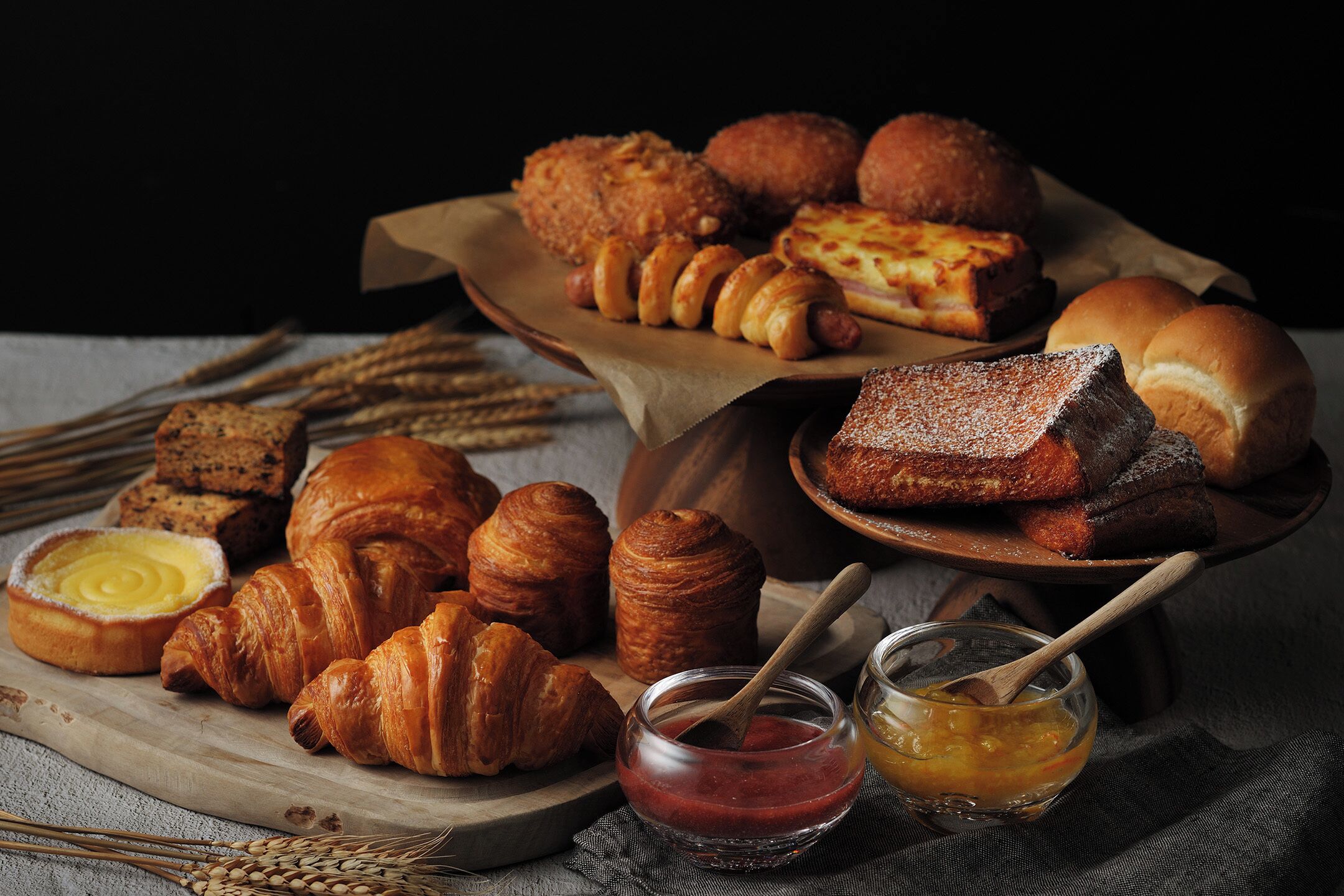A variety of baked goods including croissants, bread, and pastries on wooden boards.