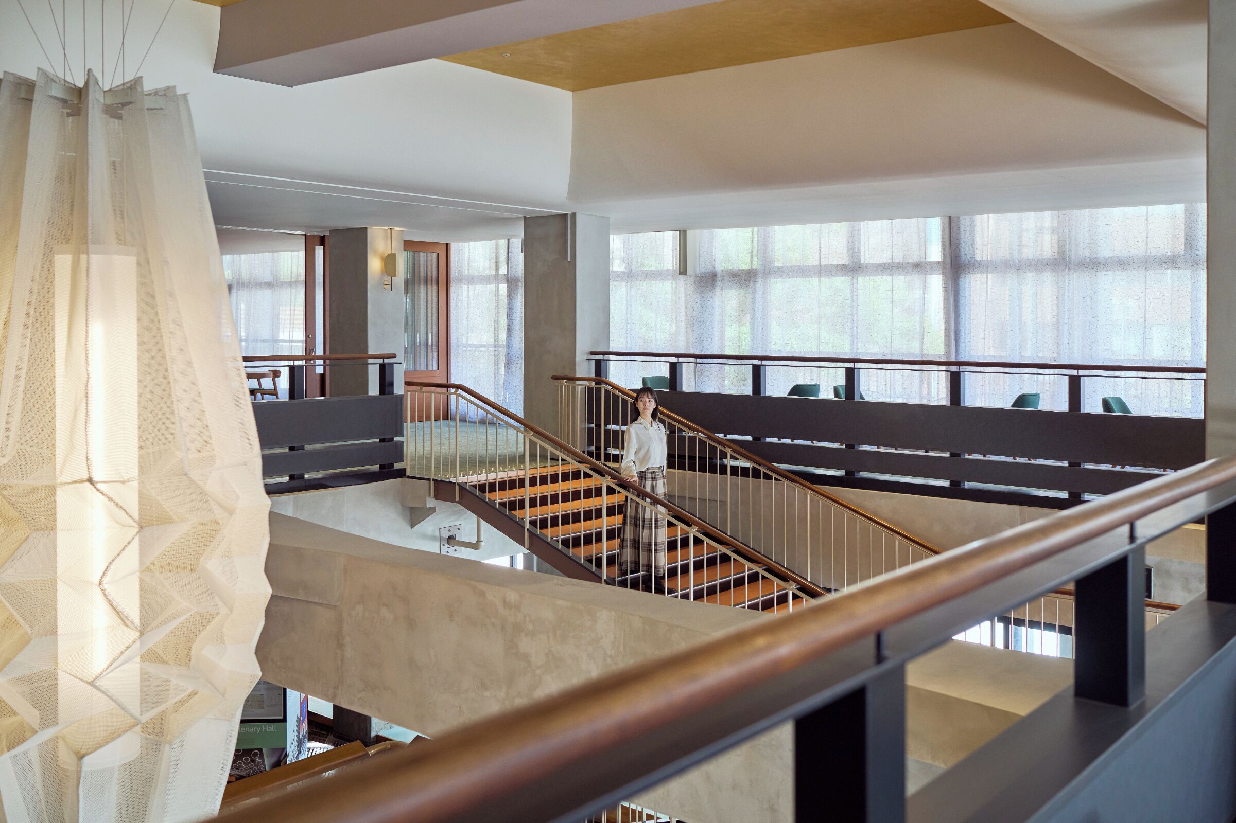 Ein modernes Interieur mit Treppe, Balkon und großen Fenstern.