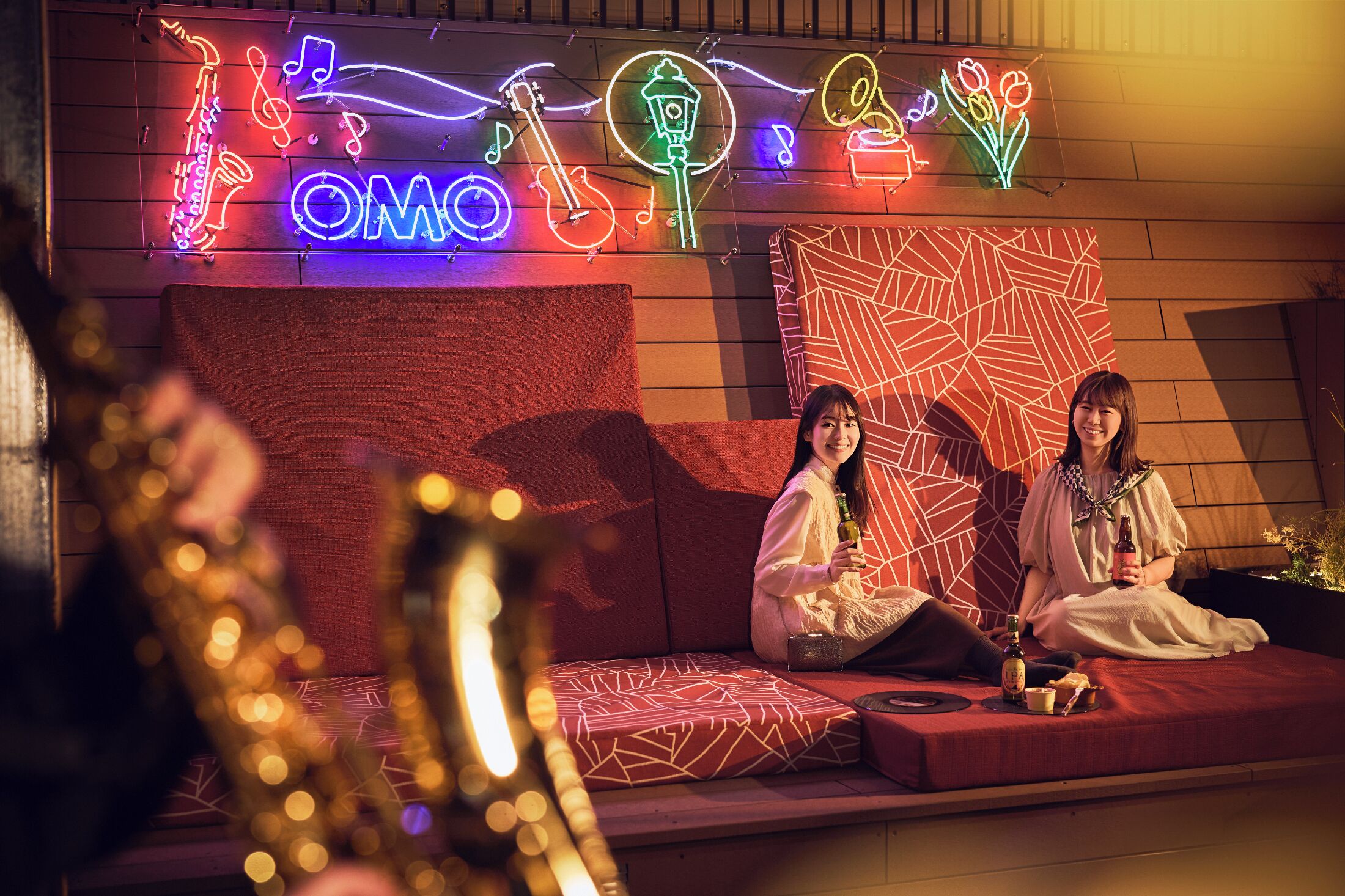 A neon-lit wall with musical instruments and the word "OMO" in the center.