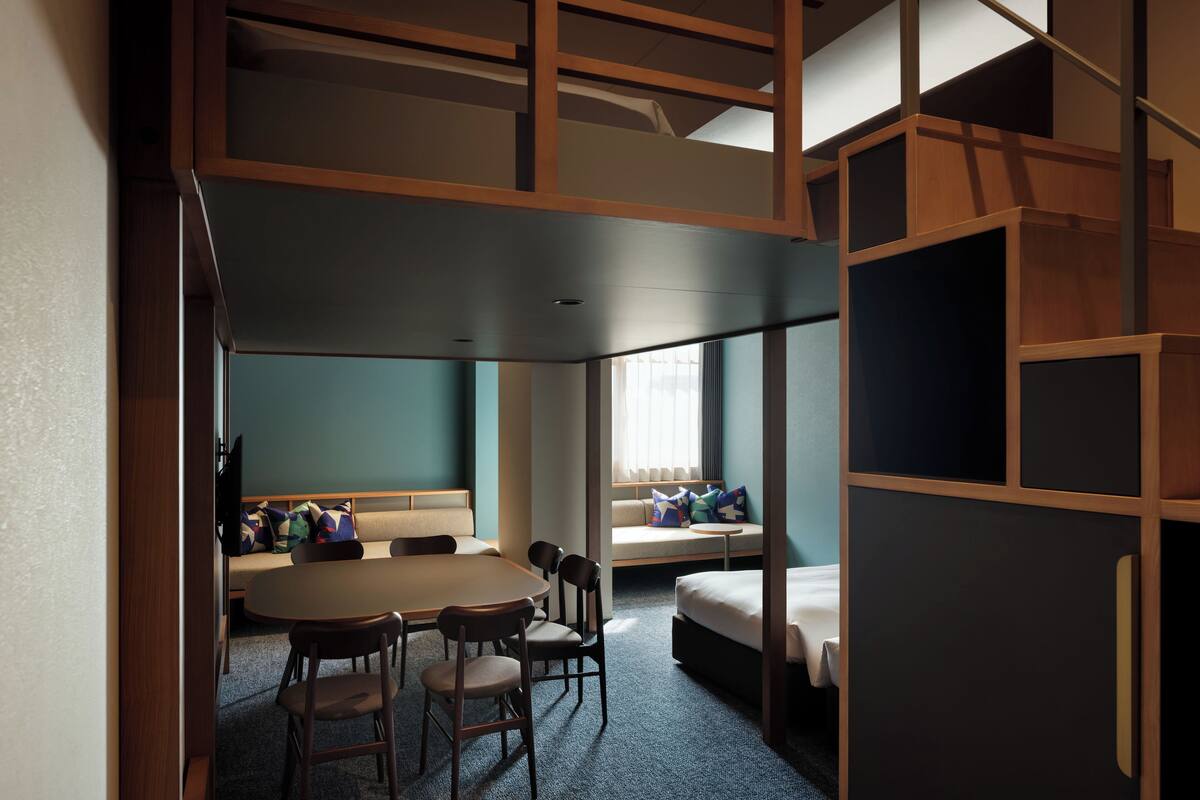 Une chambre d’hôtel avec un lit, un canapé, une table à manger avec des chaises et une petite fenêtre donnant sur un paysage agréable.