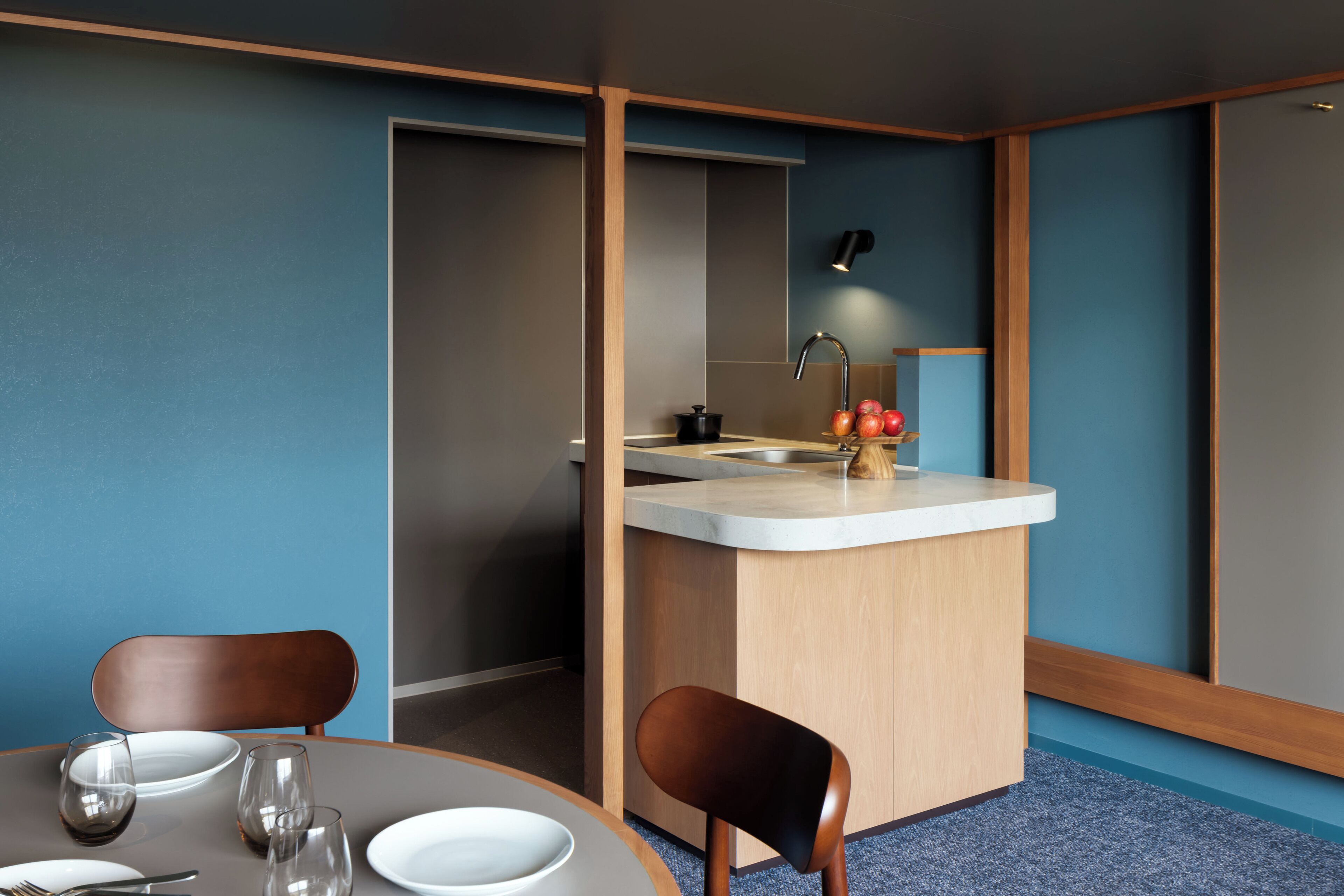 Una habitación de hotel compacta con comedor, kitchenette y pequeño bar.