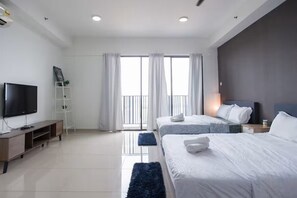 A modern hotel room with a flat-screen TV, a wooden console table, two beds with white bedding, a dark blue rug, and a balcony with curtains. - ICity Luxury Condo by Smarthome (Shah Alam)